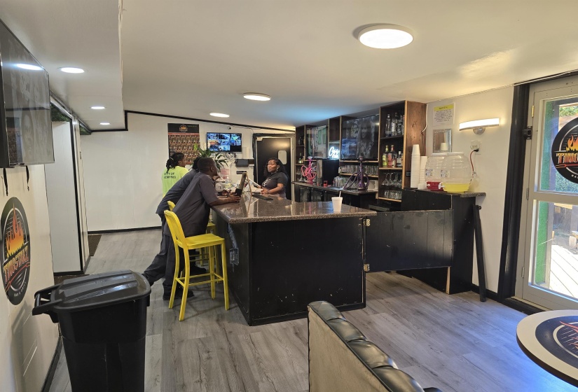 Community bar area featuring light wood-style flooring and recessed lighting