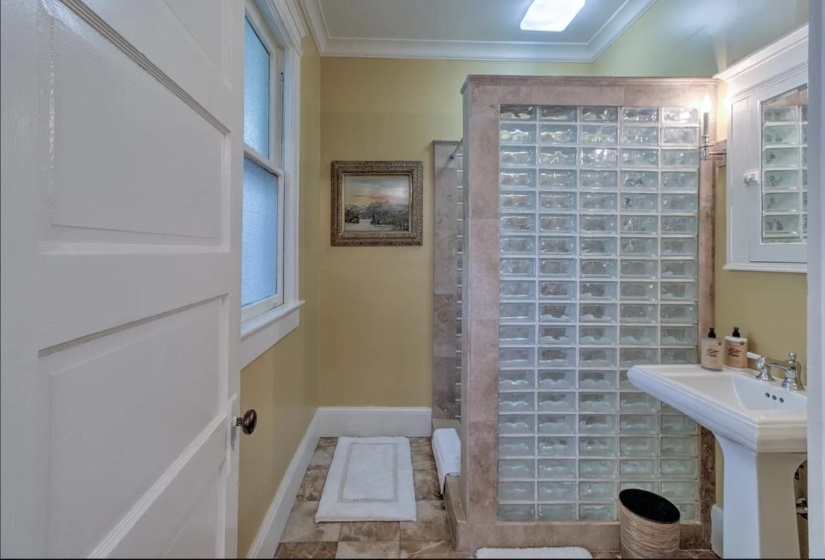 Full bathroom with tiled shower, ornamental molding, and a sink