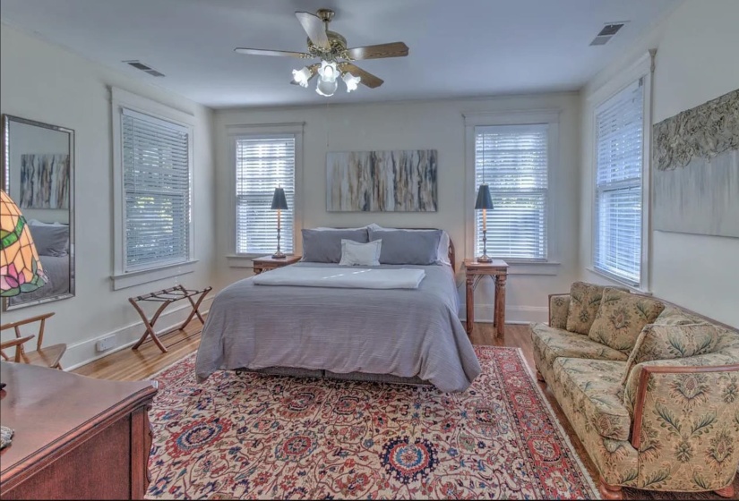 Bedroom featuring wood finished floors, multiple windows, baseboards, and a ceiling fan