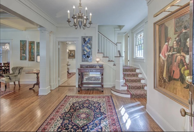 Entryway with wood finished floors, stairway, a chandelier, baseboards, and ornamental molding