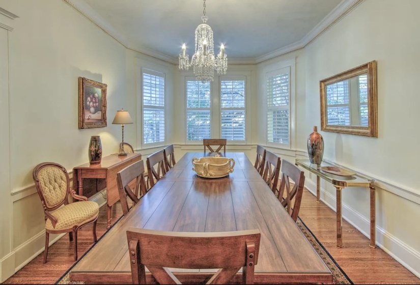 Dining room with wood finished floors, crown molding, and a chandelier