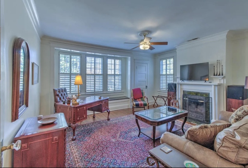 Living area with ornamental molding, a ceiling fan, a fireplace with flush hearth, and wood finished floors