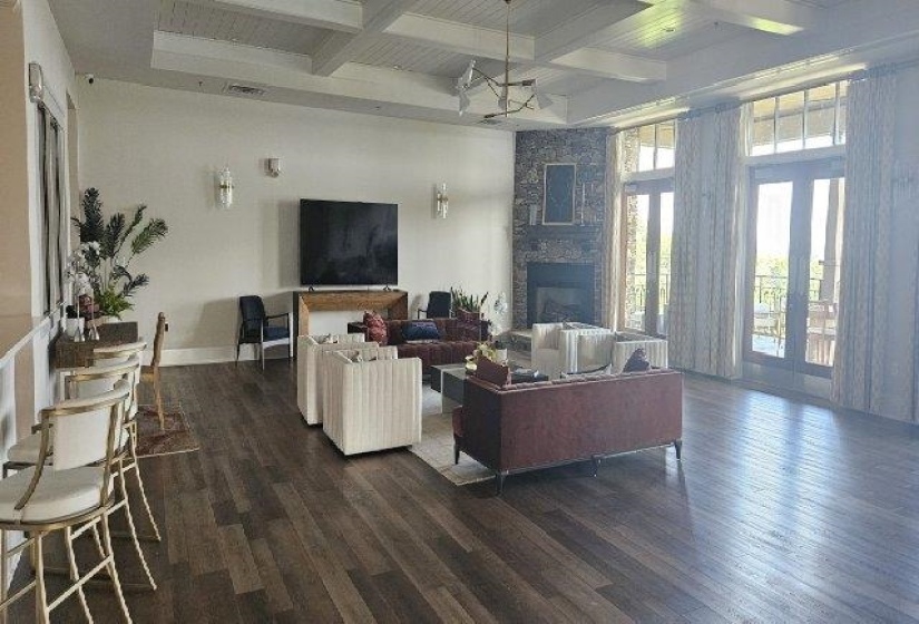 Living room featuring dark wood-style floors, coffered ceiling, beamed ceiling, baseboards, and a stone fireplace