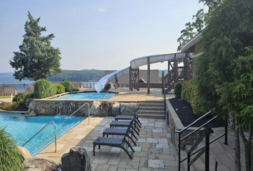 View of pool featuring a water slide, stairs, and a patio area