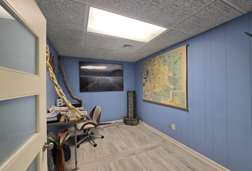 Office space with wood finished floors, a decorative wall, and baseboards