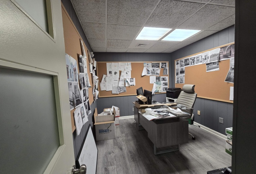 Office space with wood finished floors, a paneled ceiling, and baseboards