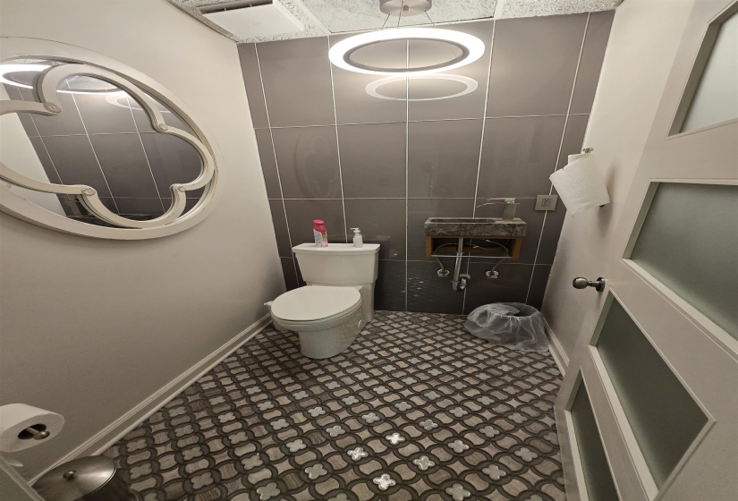 Bathroom with toilet, baseboards, and tile walls