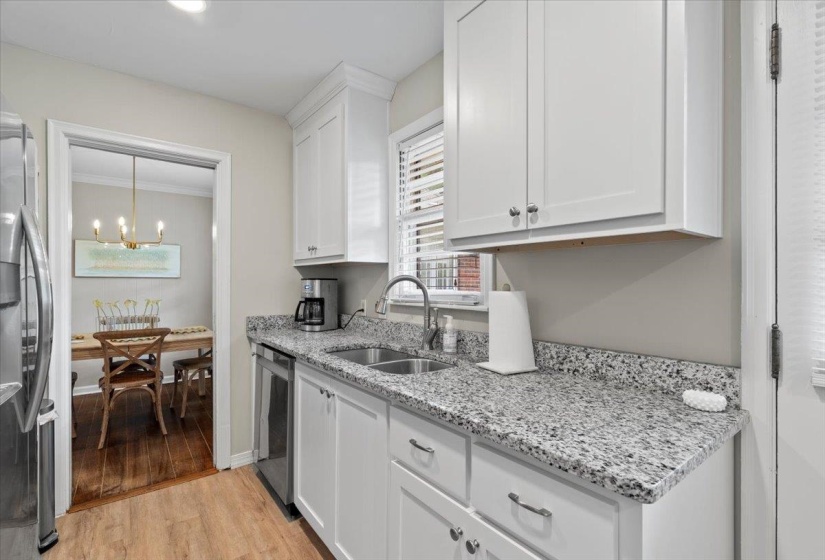 Kitchen featuring appliances with stainless steel finishes, a sink, white cabinetry, a chandelier, and light wood-type flooring