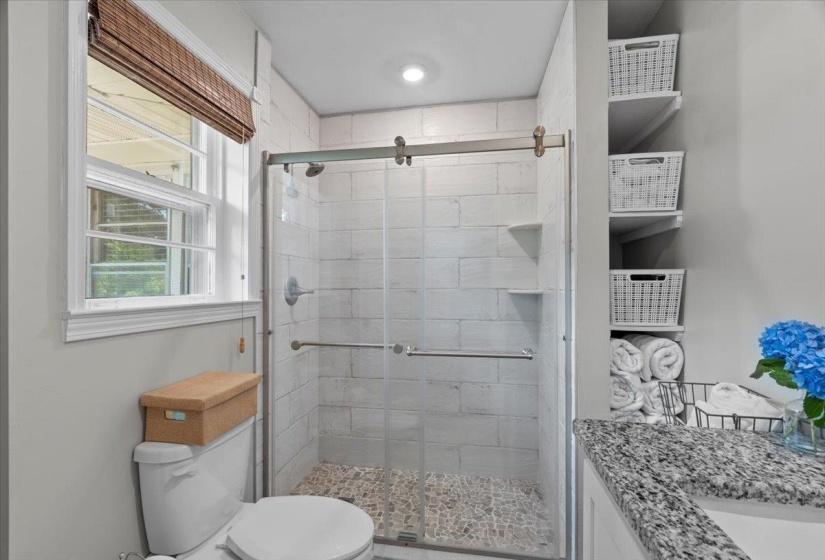 Bathroom with toilet, vanity, and a stall shower