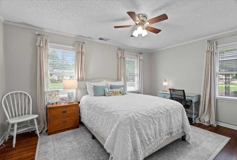 Bedroom with multiple windows, wood finished floors, a textured ceiling, crown molding, and ceiling fan