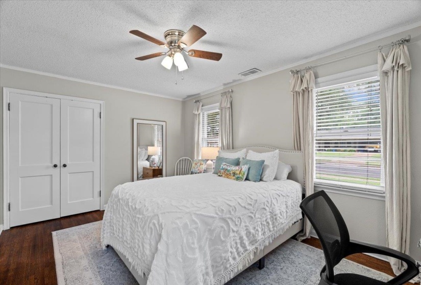 Bedroom featuring dark wood-type flooring, a textured ceiling, crown molding, and a ceiling fan