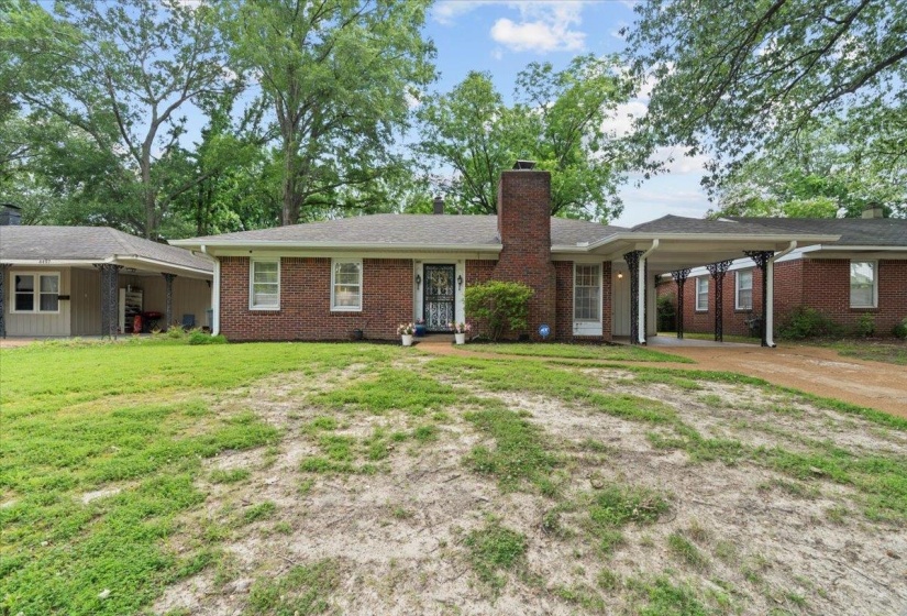 Ranch-style home with a chimney, driveway, brick siding, a front lawn, and a carport