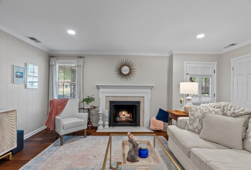 Living area featuring wood finished floors, ornamental molding, a fireplace, baseboards, and recessed lighting