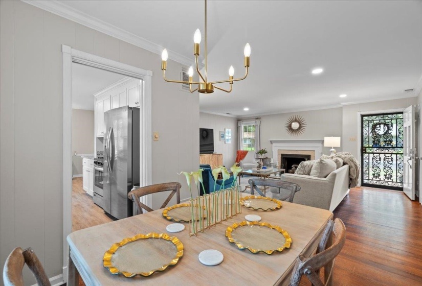 Dining room with ornamental molding, light wood finished floors, a chandelier, a fireplace, and recessed lighting