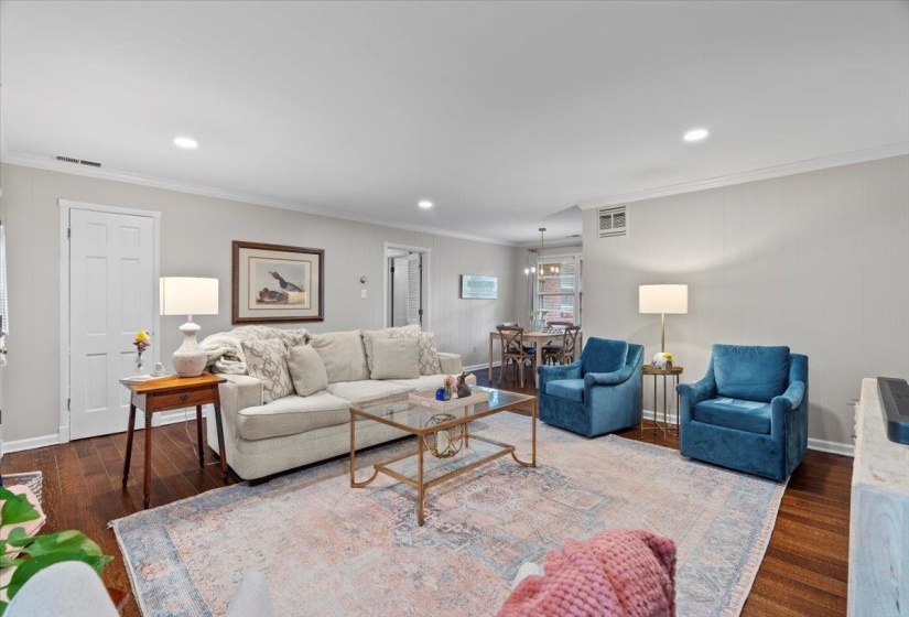 Living area with wood finished floors, crown molding, recessed lighting, and baseboards