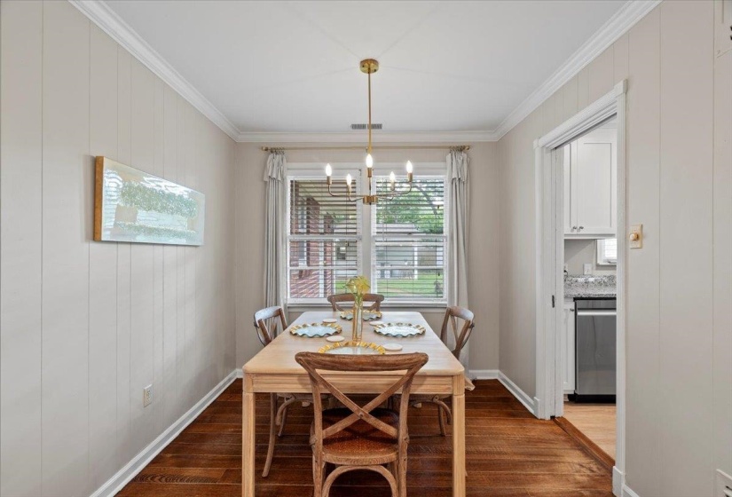 Dining space with wood finished floors, a chandelier, crown molding, and baseboards