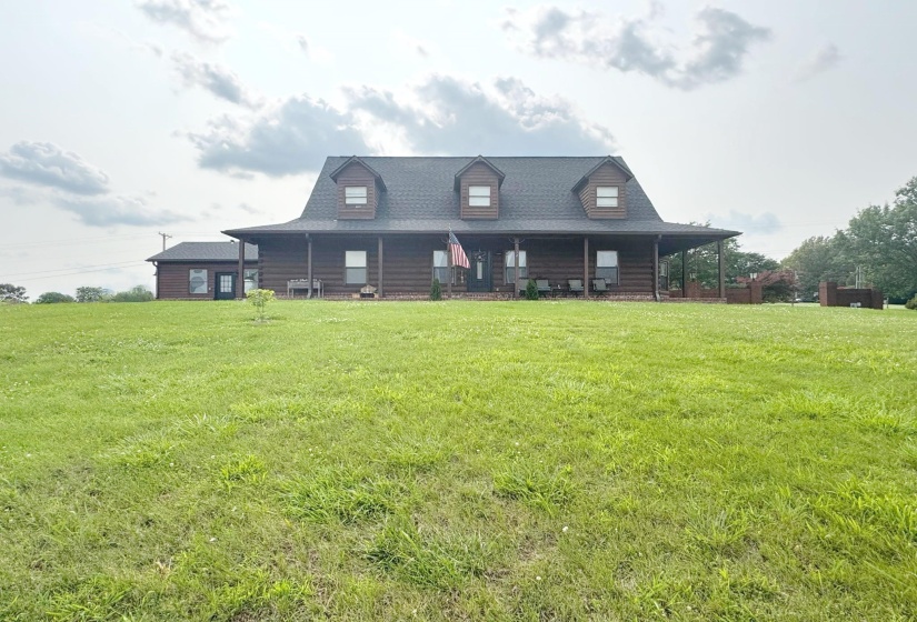 View of front of house with a porch, a front yard, and roof with shingles