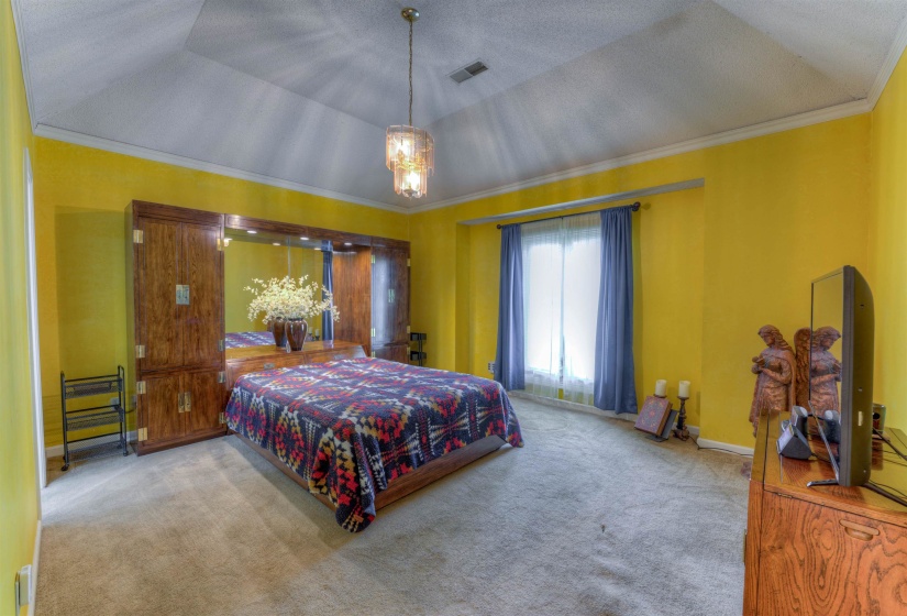 Carpeted bedroom featuring a chandelier, crown molding, and a tray ceiling