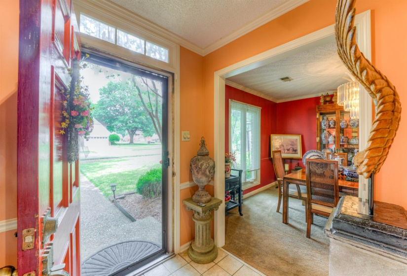 Carpeted entrance foyer with ornamental molding, tile patterned floors, and a textured ceiling
