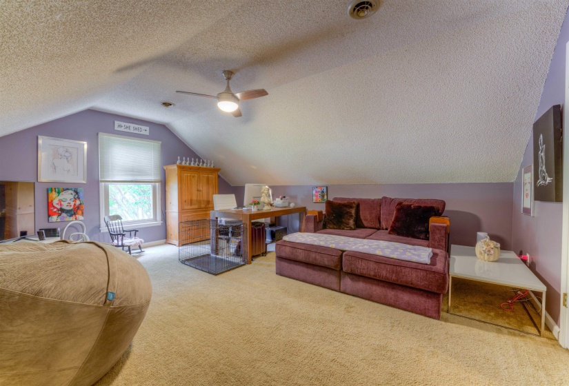 Bedroom with light carpet, a textured ceiling, vaulted ceiling, baseboards, and a ceiling fan