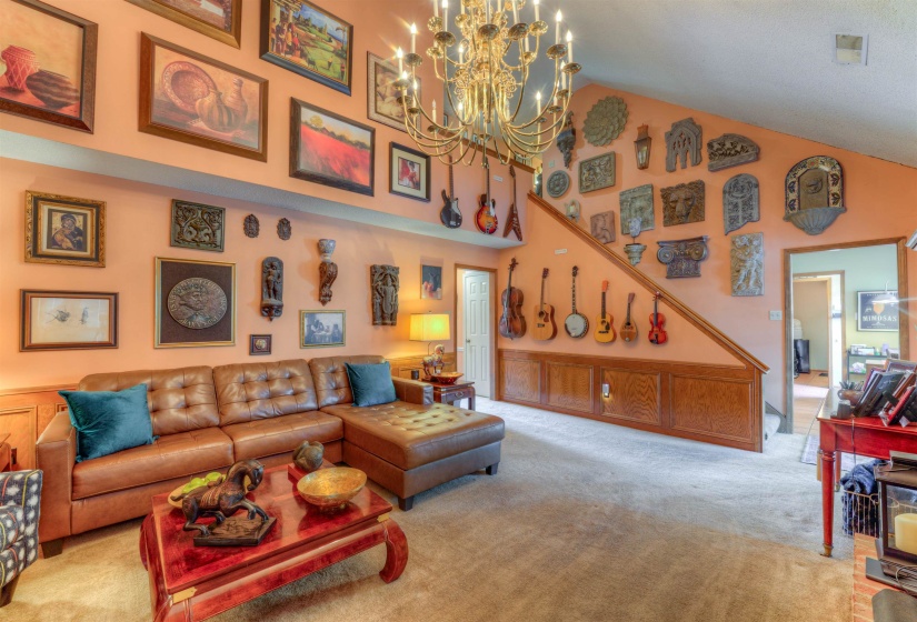Carpeted living room featuring a chandelier and high vaulted ceiling