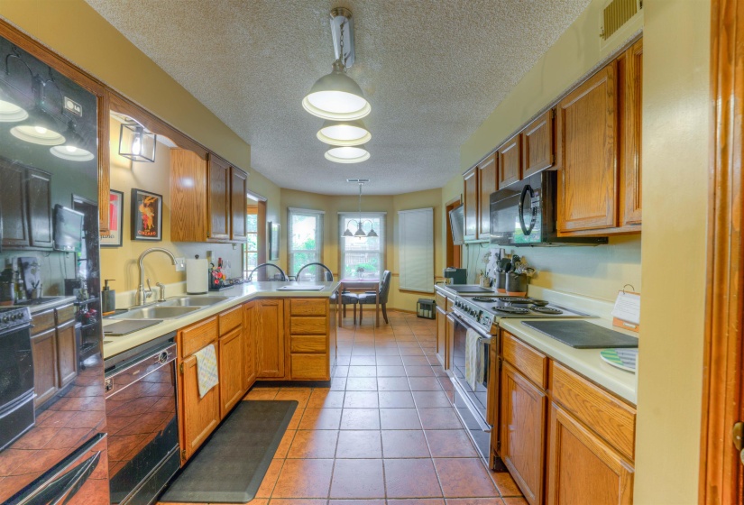 Kitchen featuring black appliances, a sink, a peninsula, hanging light fixtures, and a textured ceiling