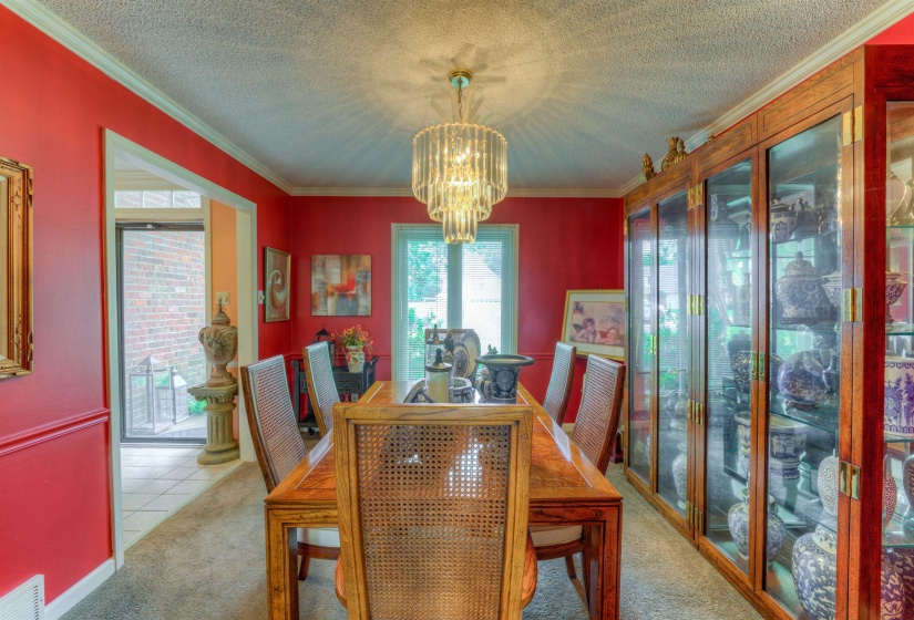 Carpeted dining room featuring a chandelier, ornamental molding, and a textured ceiling