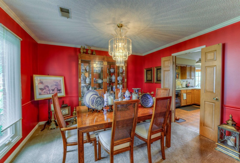 Carpeted dining area featuring a chandelier, a textured ceiling, crown molding, and a sink