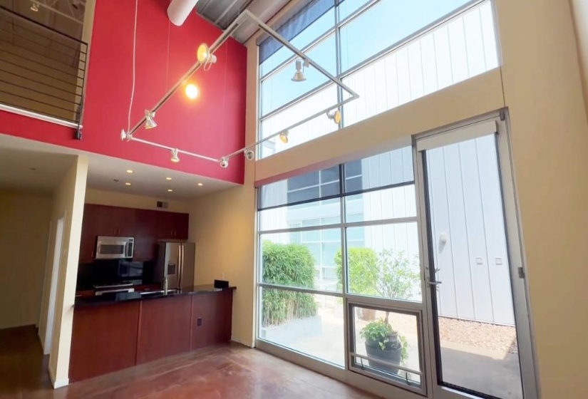 Kitchen featuring appliances with stainless steel finishes, a towering ceiling, and dark countertops