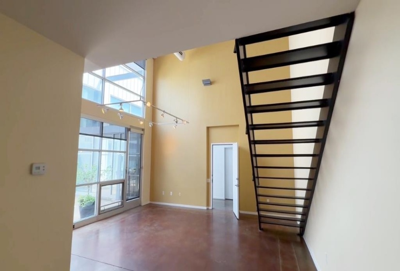 Unfurnished living room with plenty of natural light, a towering ceiling, and finished concrete floors