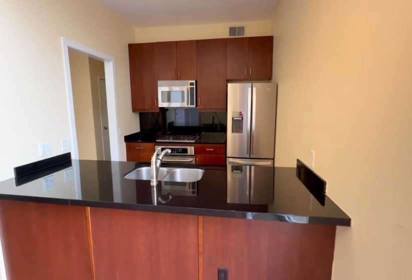Kitchen featuring appliances with stainless steel finishes, a peninsula, and dark countertops