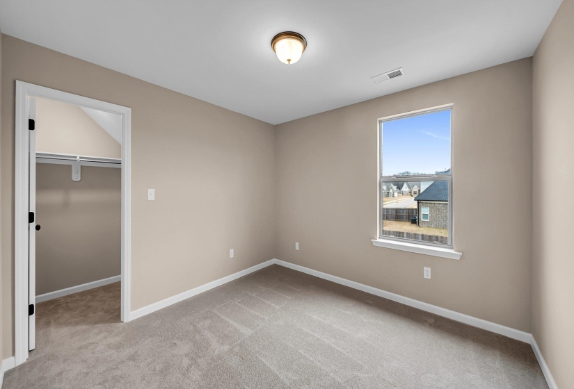Unfurnished bedroom with light carpet, visible vents, baseboards, a closet, and a walk in closet