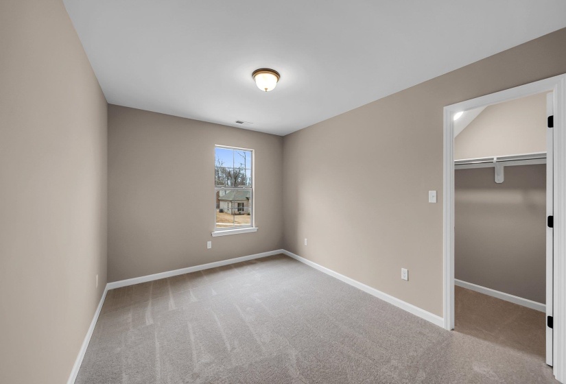 Unfurnished bedroom featuring light carpet, visible vents, baseboards, a closet, and a walk in closet