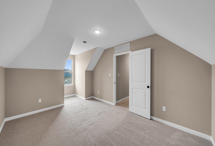 Additional living space featuring light carpet, lofted ceiling, visible vents, and baseboards