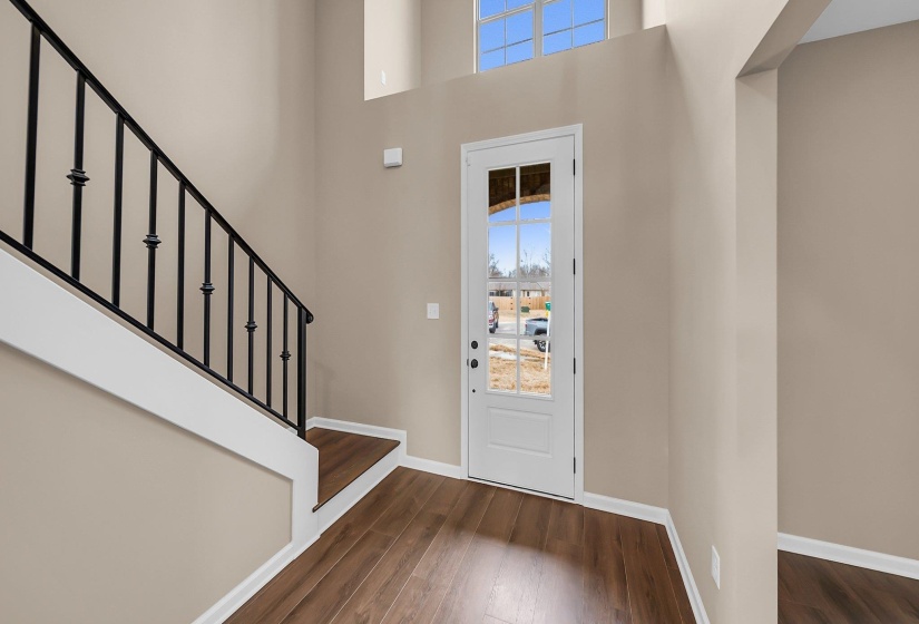 Foyer featuring a towering ceiling, stairway, baseboards, and dark wood finished floors