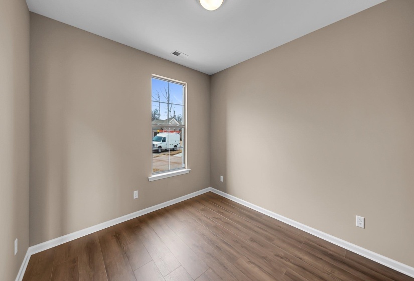 Spare room with wood finished floors, visible vents, and baseboards