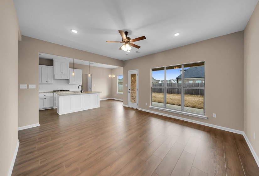 Unfurnished living room featuring a sink, baseboards, dark wood-style flooring, and ceiling fan with notable chandelier