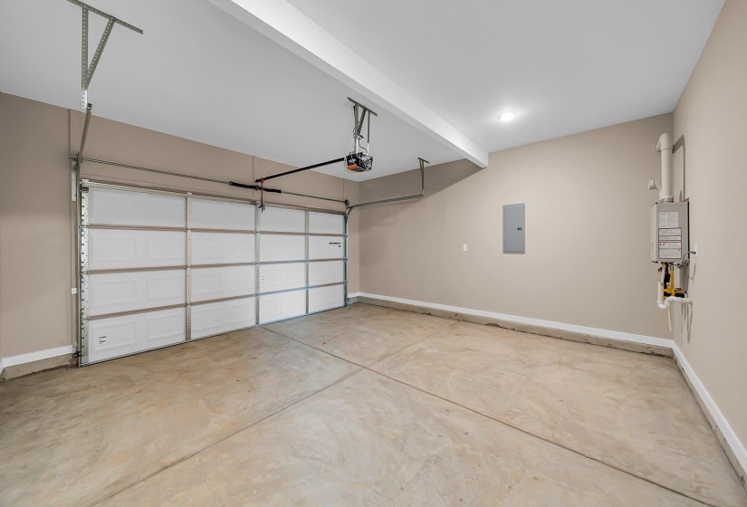 Garage with a garage door opener, electric panel, baseboards, and water heater