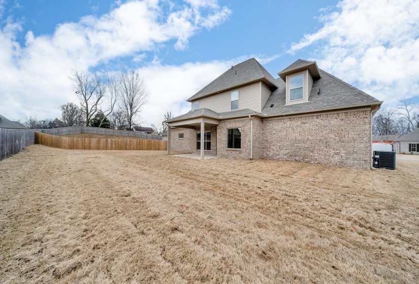 Rear view of house with brick siding, roof with shingles, central AC unit, and a fenced backyard