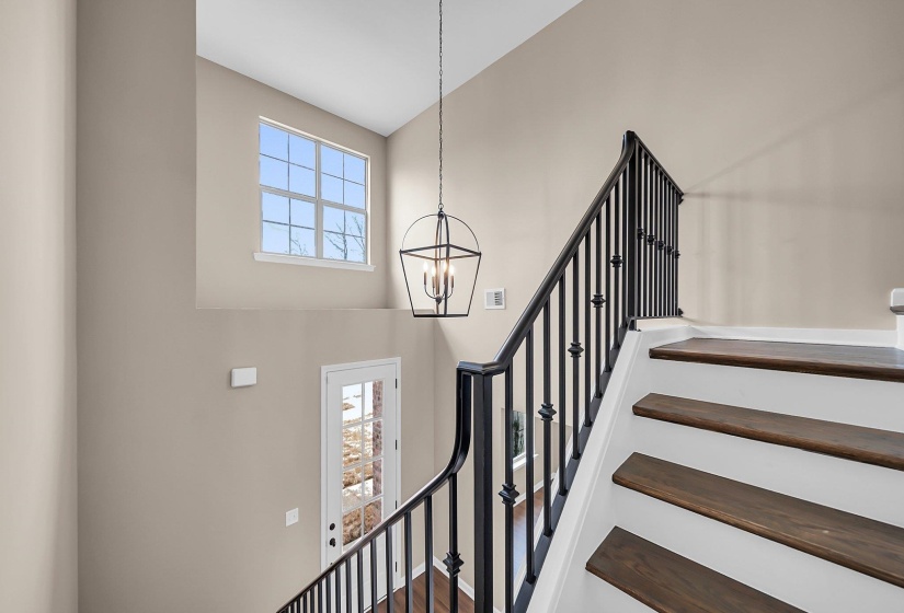 Stairs featuring a towering ceiling, visible vents, and a notable chandelier