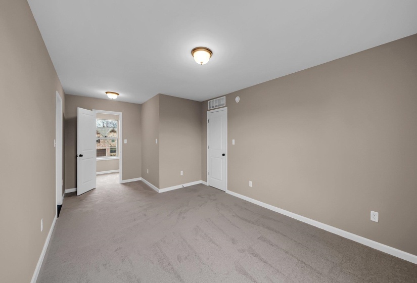 Empty room with light colored carpet, visible vents, and baseboards