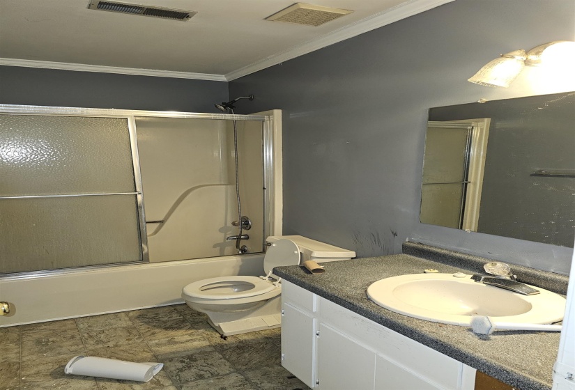 Bathroom featuring crown molding, vanity, and enclosed tub / shower combo