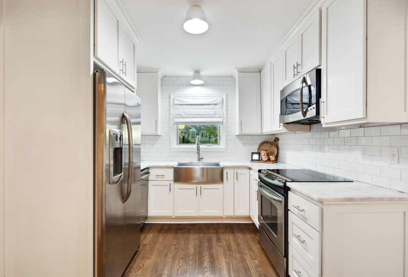 Kitchen featuring backsplash, stainless steel appliances, dark wood-type flooring, and a sink