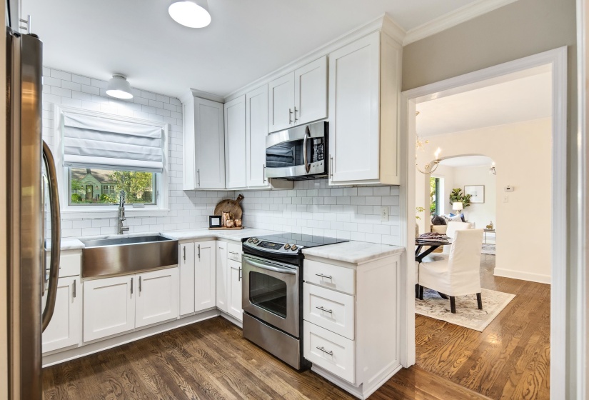 Kitchen featuring white cabinets, stainless steel appliances, a sink, a chandelier, and decorative backsplash
