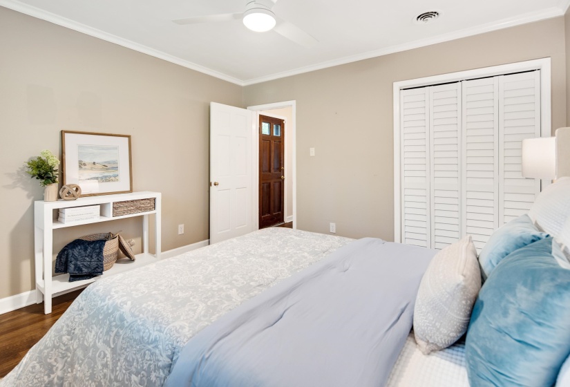 Bedroom featuring dark wood-style floors, baseboards, visible vents, a closet, and ornamental molding