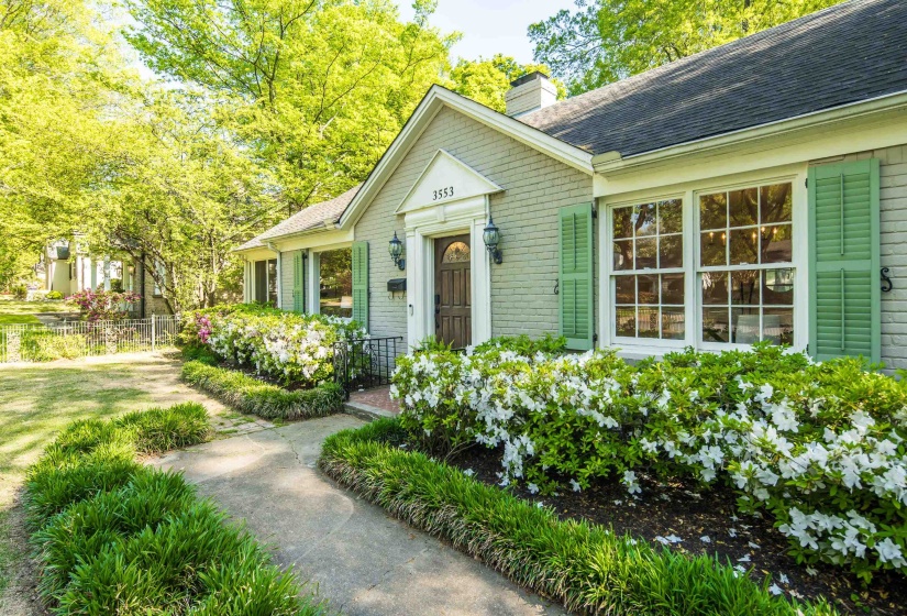 View of front facade with brick siding, roof with shingles, a chimney, and fence