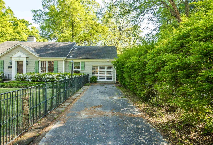 View of front of house featuring driveway, a chimney, and fence