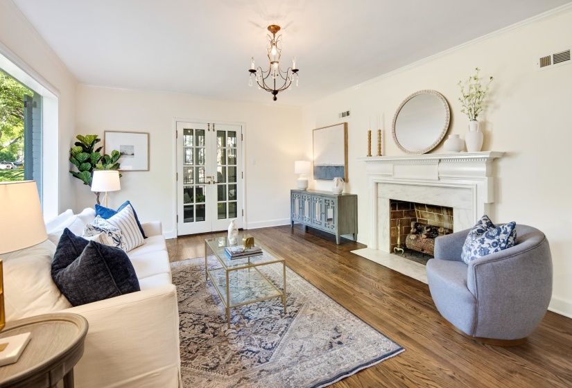 Living area with wood finished floors, visible vents, an inviting chandelier, and a high end fireplace