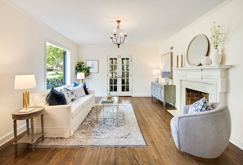 Living area featuring a fireplace with flush hearth, wood finished floors, baseboards, and a notable chandelier