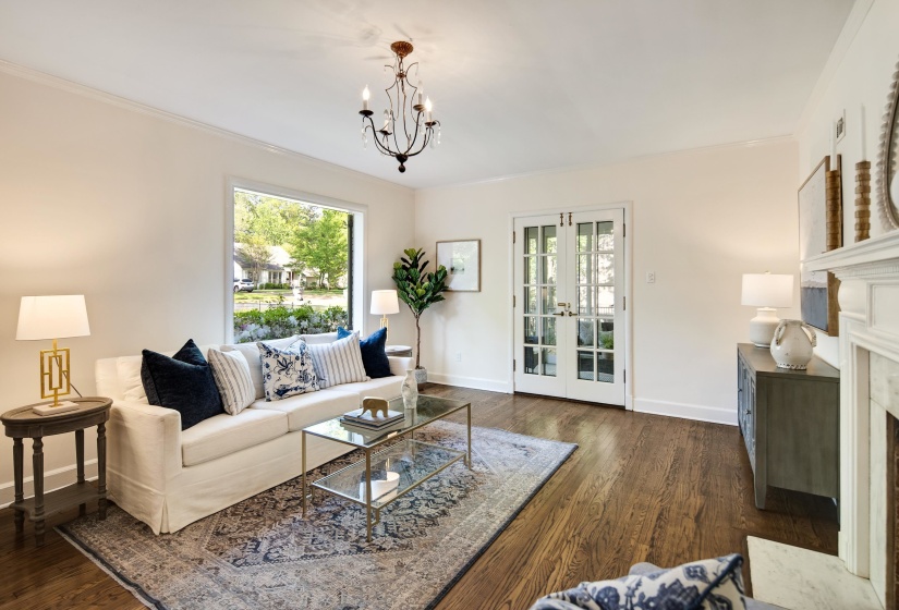 Living room featuring an inviting chandelier, wood finished floors, ornamental molding, baseboards, and a fireplace